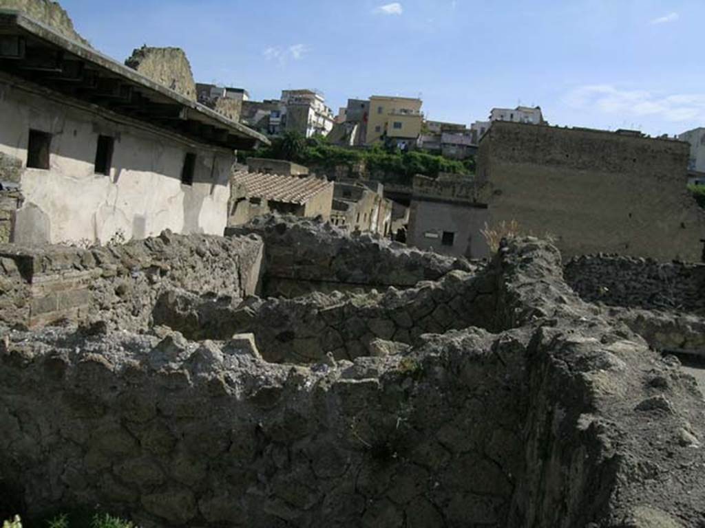 IV.3/4, Herculaneum, May 2005.
Upper floor, looking north towards III.11 (white building, on left), and fullonica at IV.5/6/7, centre.
Photo courtesy of Nicolas Monteix.
According to Monteix, on the west side of the upper floor were three rectangular tubs/basins used as an attic granary.
Found: 30th November 1928, at the back of the wall was found a rectangular tub/basin 2.09m long, by 1.54m wide, with a depth of 0.86m.
In it was a deposit of cereals, grain, inventory no.378.
Found: 8th January 1929, the two tubs placed to the north of the already described on 30th November have been excavated.
The second was 2.10m long, 1.50m wide, and 0.85 deep. The walls were completely covered with plaster. The base was of cocciopesto and reasonably conserved. No objects were found.
The third was 2.10m long, 1.80m wide, and 0.85m deep. No objects……
See Monteix, N. 2008. La conservation des denrées dans l’espace domestique à Pompéi et Herculanum, MEFRA 120-1, p. 131.